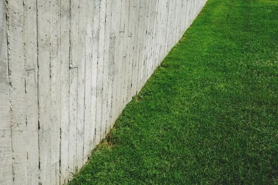A minimalist outdoor scene featuring a wooden fence alongside a lush green lawn.